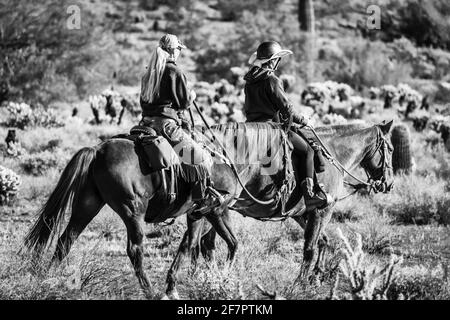 Fotografia in bianco e nero di due donne che cavalcano i loro cavalli all'Apache Wash Trailhead a Phoenix, Arizona. Foto Stock