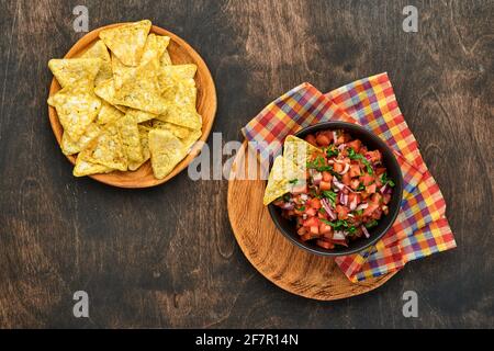 Salsa di pomodoro tradizionale messicana con nachos e ingredienti pomodori, cile, aglio, cipolla su sfondo scuro vecchio legno. Concetto di Amer Latina Foto Stock