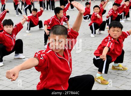 (210409) -- DENGFENG, 9 aprile 2021 (Xinhua) -- Huang Yuxuan (fronte) della squadra di hockey su ghiaccio Shaolin Tagou pratica le arti marziali nella scuola di arti marziali di Shaolin Tagou, città di Dengfeng, provincia centrale di Henan, 31 marzo 2021. La Shaolin Tagou Martial Arts School, a pochi chilometri dal tempio Shaolin, luogo di nascita di Shaolin Kung fu, sta costruendo la sua squadra di hockey su ghiaccio. Gli studenti imparano lo sport sui pattini a rotelle in una pista di dimensioni standard coperta di pavimento, invece che di ghiaccio. Praticare le arti marziali rafforza i loro fisiques e fornisce loro le qualità atletiche che hockey su ghiaccio richiede Foto Stock