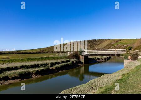 Il fiume Cuckmere nelle Downs Sud con la Litlington White Horse su una collina in lontananza Foto Stock