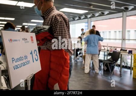 Madrid, Spagna. 9 aprile 2021: Un uomo che passa davanti a un posto di vaccinazione al Wizink Centre. Il WiZink Centre di Madrid, precedentemente noto come Palacio de los Deportes, è uno degli spazi polivalenti più versatili della Spagna in cui si svolgono eventi sportivi, spettacoli, fiere e concerti, Ora sta anche diventando un centro di vaccinazione contro Covid-19. Un credito USA/A: Sipa USA / Alamy Live News Foto Stock