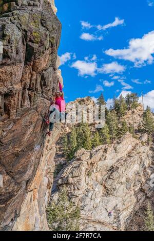 Donna rock climber la naviga su una parete rocciosa in Golden, CO Foto Stock
