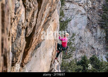 Donna rock climber la naviga su una parete rocciosa in Golden, CO Foto Stock