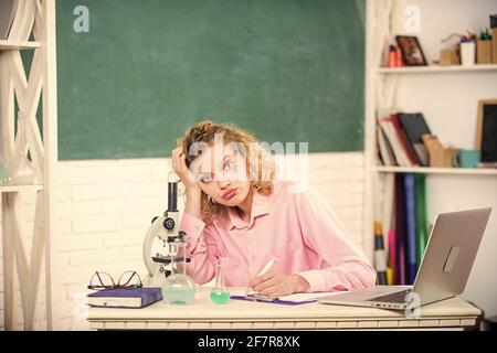 Lavoro stressante dell'insegnante. Pressione nervosa tesa. Ragazza stanca espressione stressante con laptop e microscopio di lavoro di ricerca biologia e. Foto Stock