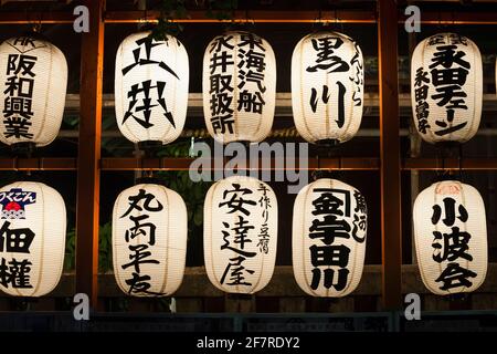 Vista orizzontale di due file di lanterne cinesi illuminate nel santuario Namiyoke-jinja Shinto di notte, Tsukiji, Tokyo, Giappone Foto Stock