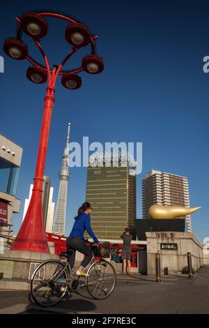 Giovane donna in bicicletta e turista che scatta foto sul ponte Azuma-Bashi con lo Sky Tree di Tokyo e la fiamma di Asahi sullo sfondo, Asakusa Foto Stock