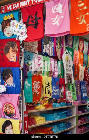 Vista ravvicinata verticale delle colorate T-shirt di un negozio Takeshita-dori, Harajuku, Tokyo, Giappone Foto Stock