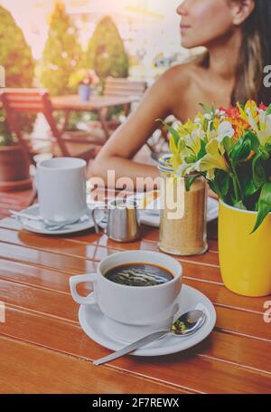 Condivisione di coppia in una caffetteria al tramonto, momento romantico con fiori, caffè e sito vintage Foto Stock