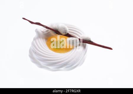 Biscotto di meringa bianco con crema di limone gialla al centro decorato con un bastone di un salice isolato su bianco. Tema di Pasqua Foto Stock