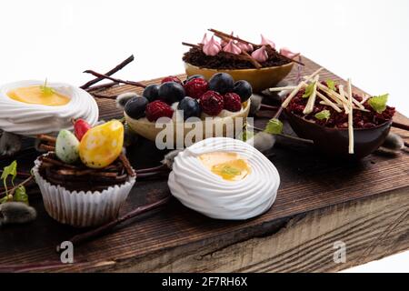 Selezione di diversi cupcake dolci, biscotti e uova di cioccolato farcite su tavola di legno Foto Stock