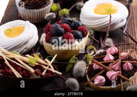 Selezione di diversi cupcake dolci, biscotti e uova di cioccolato farcite su tavola di legno Foto Stock
