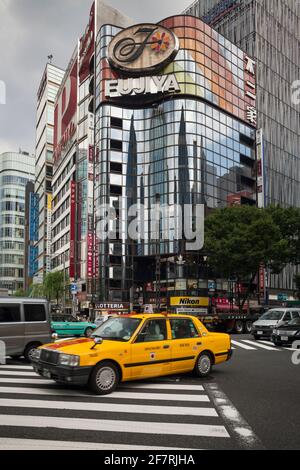 Vista verticale di un taxi giallo sulla via Sukiyabashi con attraversamento pedonale di Harumi-dori Ave, Ginza, Tokyo, Giappone Foto Stock