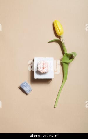 concetto di design organico. Stile scandinavo: Rosa su marmo, tulipano giallo e minerale di cristallo su sfondo beige. Foto Stock