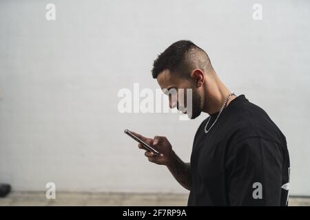 Spagnolo maschio utilizzando un telefono all'aperto Foto Stock