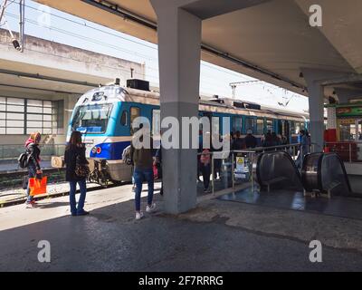 Salonicco, Grecia, passeggeri in attesa di salire a bordo di un pullman ferroviario. Folla non identificata accanto a una locomotiva ferma su una piattaforma di binario della stazione ferroviaria. Foto Stock