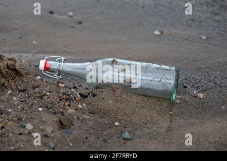 Bottiglia di vetro sulla spiaggia sabbiosa, Foto Stock