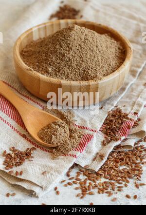 Farina cruda di semi di Flax in una ciotola di legno con un cucchiaio Foto Stock