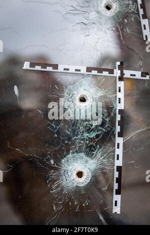 buchi di proiettile in una vetreria contrassegnata con una nastro di polizia Foto Stock