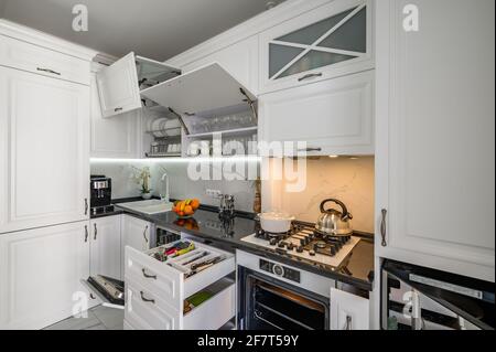 Lussuoso interno bianco moderno cucina, cassetti estraibili, porte aperte Foto Stock