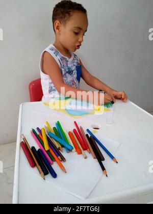 salvador, bahia / brasile - 18 novembre 2020: Il bambino si vede dipingere un disegno della bandiera del Brasile durante le attività scolastiche. Foto Stock