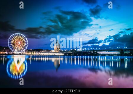 Tolosa, Occitania, Francia; 21 luglio 2018: Tramonto sul fiume Garone con l'ospedale, il ponte di Saint Pierre e la ruota panoramica sull'altro Foto Stock
