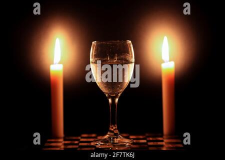 Due candele e un bicchiere d'acqua ghiacciata Foto Stock