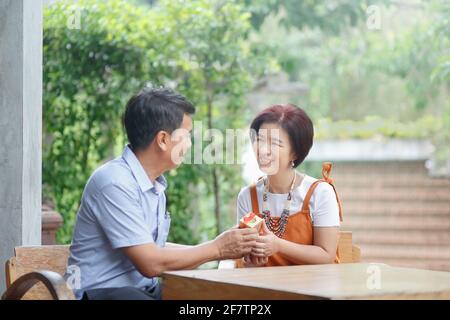 L'uomo di mezza età asiatico dà un regalo a sua moglie dentro giorno di nozze anniversario Foto Stock