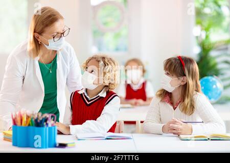 Bambini in maschera facciale in classe scolastica. Il bambino torna a scuola dopo il blocco del coronavirus. Bambino primario nella pandemia di covid-19. Foto Stock