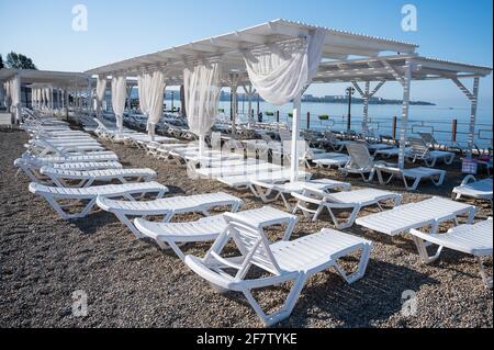 Sedie a sdraio vuote su una spiaggia di ciottoli. Foto Stock