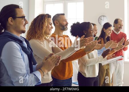 Gruppo di persone felici e diverse che applaudono ringraziando l'oratore per la gioia presentazione Foto Stock