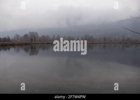 Tranquillo lago circondato da alberi d'autunno e montagne Foto Stock