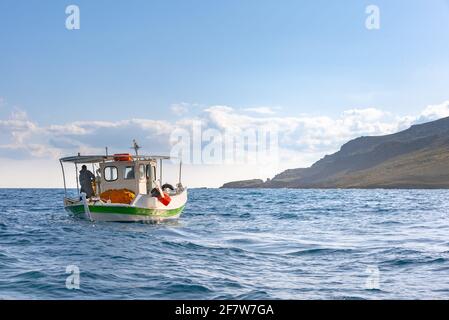 Il pescatore sta pescando i pesci freschi usando le reti da pesca gialle, sulla barca da pesca, Creta, Grecia Foto Stock