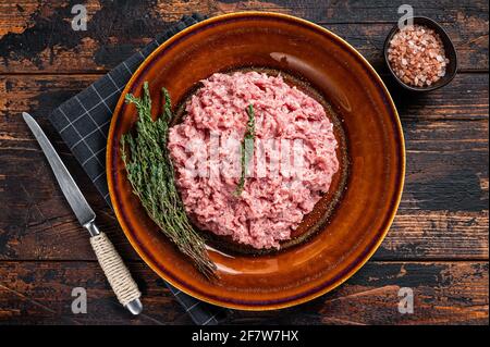 Pollo macinato o carne di tacchino, pollame crudo su piatto rustico con erbe. Sfondo scuro. Vista dall'alto Foto Stock