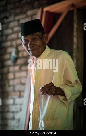 MANINJAU, INDONESIA - 12 febbraio 2021: Vecchio che si gode la sua sigaretta fatta a mano. Foto Stock