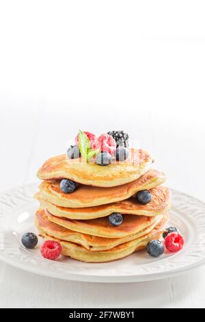Frittelle dorate americane con sciroppo d'acero e bacche. Pancake per colazione. Foto Stock