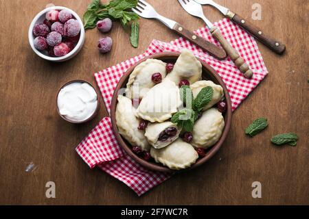 Pierogi con ciliegie. Gnocchi Vareniki. Cibo tradizionale ucraino. Cucinato e servito con panna acida e bacca Foto Stock