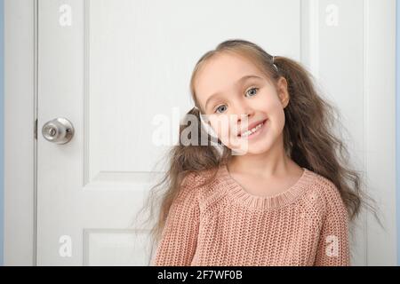 Carina bambina in piedi vicino alla porta chiusa Foto Stock