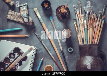 Pennello e tubi con strumenti di pittura a trama astratta di sfondo tabella. Concept e pennello per pittura d'arte Foto Stock