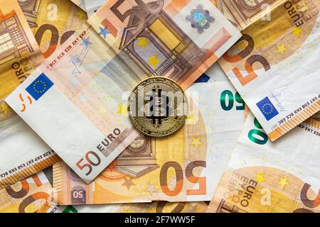 Vista dall'alto di una moneta di bit su uno sfondo di 50 euro di bollette. Bitcoin come nuovo denaro, mercato azionario di criptovalute e concetto di finanze decentralizzate Foto Stock