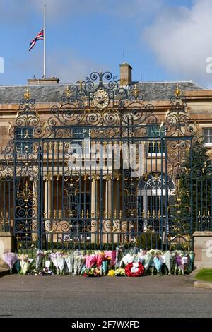 Hillsborough Castle, Hillsborough, County Down, Irlanda del Nord, Regno Unito. 10 aprile 2021. Con la bandiera dell'Unione a metà albero, i tributi floreali sono stati lasciati fuori dalle porte della residenza ufficiale della regina HM in Irlanda del Nord, come il pubblico piange la perdita del principe Filippo, duca di Edimburgo, che è morto ieri. Credit: David Hunter/Alamy Live News. Foto Stock