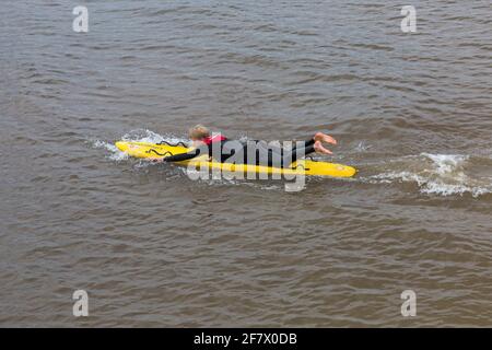 Bournemouth, Dorset UK. 10 aprile 2021. Tempo nel Regno Unito: Fresco, nuvoloso e grigio, come poche persone si dirigano verso il mare a Bournemouth spiagge per un po 'di esercizio. RNLI Lifeguard effettua alcuni allenamenti in preparazione di una stagione impegnativa in mare sulla sua tavola da surf. Credit: Carolyn Jenkins/Alamy Live News Foto Stock