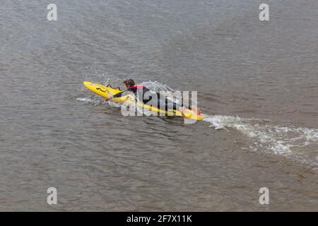 Bournemouth, Dorset UK. 10 aprile 2021. Tempo nel Regno Unito: Fresco, nuvoloso e grigio, come poche persone si dirigano verso il mare a Bournemouth spiagge per un po 'di esercizio. RNLI Lifeguard Tim effettua alcuni allenamenti in preparazione di una stagione impegnativa in mare sulla sua tavola da surf. Credit: Carolyn Jenkins/Alamy Live News Foto Stock