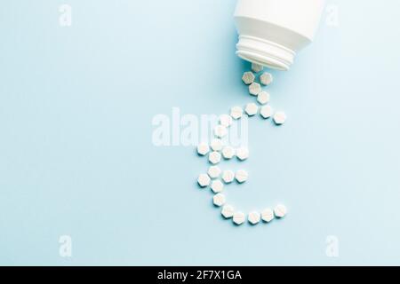 Pillole di medicina forma euro con bottiglia su sfondo blu. Concetto di guadagni.