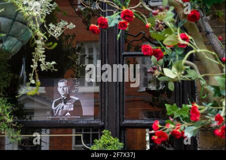 Windsor, Berkshire, Regno Unito. 10 aprile 2021. Una fotografia di S.A.R. il Principe Filippo nella finestra del pub dei due Brewers dove il Duca di Edimburgo era conosciuto per aver visitato. Centinaia di persone erano a Windsor oggi portando tributi floreali per la regina Elisabetta II dopo la triste scomparsa di suo marito, il duca di Edimburgo ieri. I fiori venivano collocati sull'erba fuori dalle porte del Castello di Windsor sulla Long Walk. Numerosi media outlet sono stati a Windsor riprese oggi. Credit: Maureen McLean/Alamy Live News Foto Stock