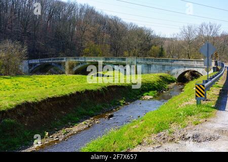 Embreeville, PA, USA - 6 aprile 2021: Un ponte ad arco attraversa il ramo occidentale del Brandywine Creek vicino a Embreeville nella contea di Chester, Pennsylvania. Foto Stock