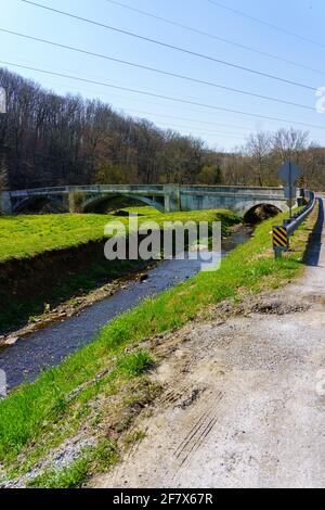 Embreeville, PA, USA - 6 aprile 2021: Un ponte ad arco attraversa il ramo occidentale del Brandywine Creek vicino a Embreeville nella contea di Chester, Pennsylvania. Foto Stock