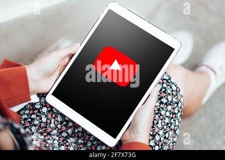 Podolsk, Ucraina - 29 marzo 2021: Le mani della donna che tengono un tablet digitale con il logo di YouTube su uno schermo visualizza l'app YouTube sul touch screen. Foto Stock