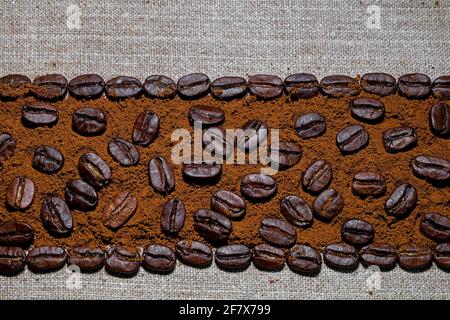 telaio foderato con chicchi di caffè neri e caffè macinato lo sfondo del panno di lino grossolano Foto Stock