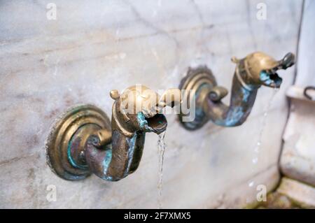 Rubinetti d'acqua in ottone su un muro di marmo nel monastero di Bachkovo Un monastero cristiano ortodosso in Bulgaria Foto Stock