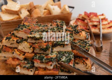 Fette di pizza a forma quadrata con crosta morbida su a. tavolo con tong da cucina Foto Stock